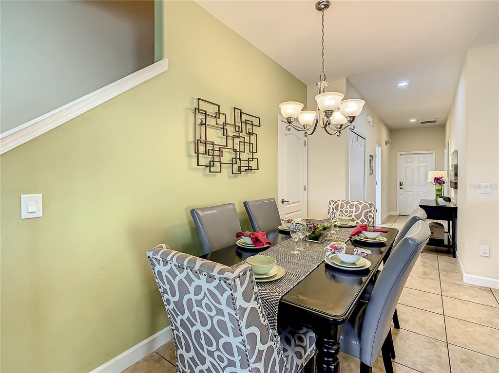 A dining room features a dark table, patterned chairs, a chandelier, and light green walls — 3039 BEACH PALM AVENUE, KISSIMMEE, FL