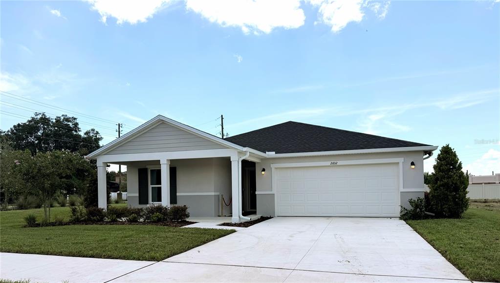 A single-story house with a white garage, a covered front porch, and a grassy lawn — 2602 LOLA LANE, KISSIMMEE, FL