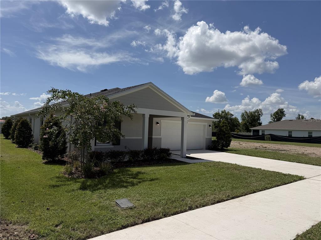 A single-story house with a two-car garage, light gray siding, and a landscaped front yard — 2602 LOLA LANE, KISSIMMEE, FL