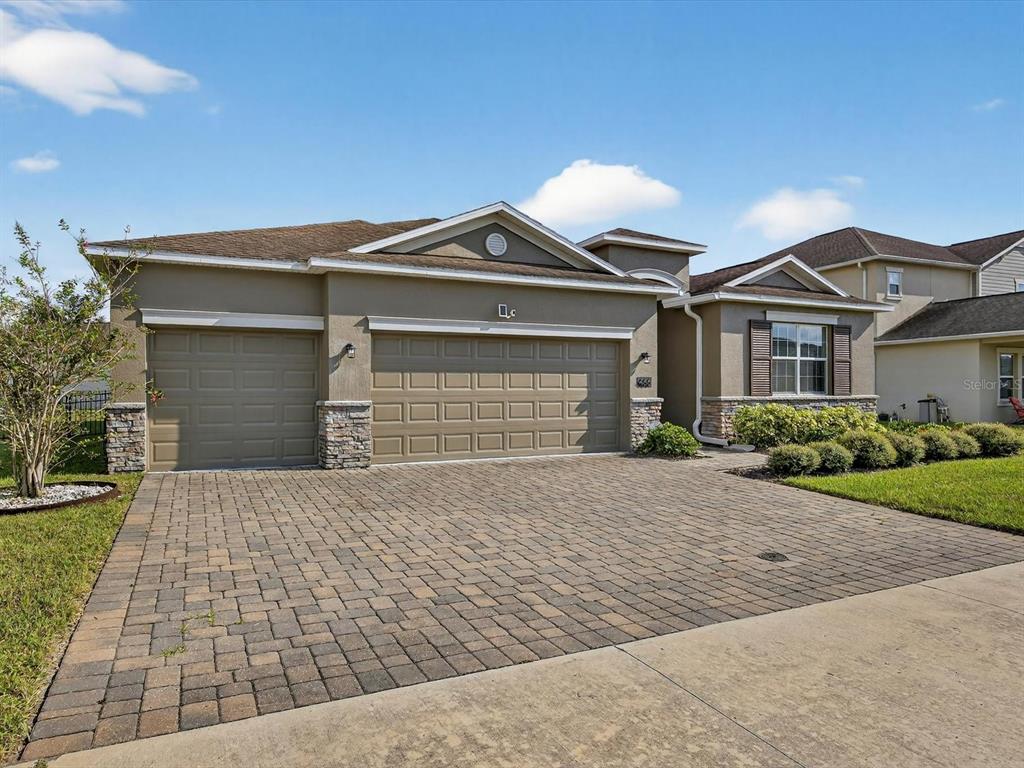 A single-story house with a paved driveway, three-car garage, and stone accents on the exterior — 466 BRUNSWICK DRIVE, DAVENPORT, FL