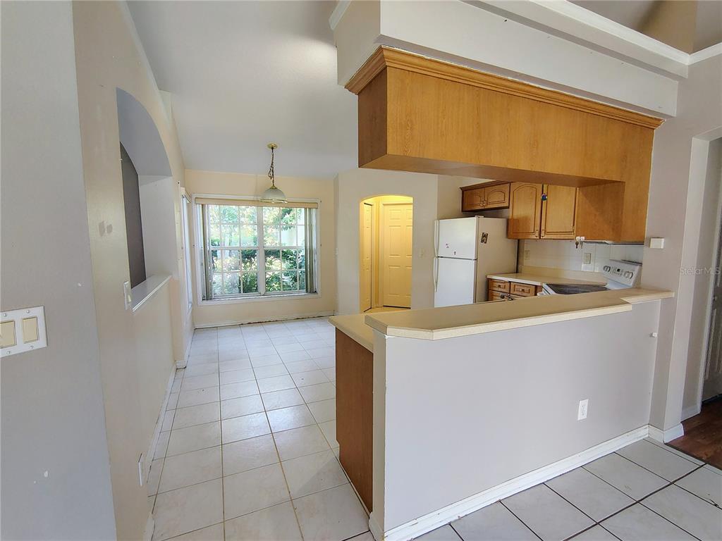 A kitchen with wood cabinets and a breakfast bar overlooks a tiled dining area — 3248 SAWGRASS CREEK CIRCLE, ST CLOUD, FL
