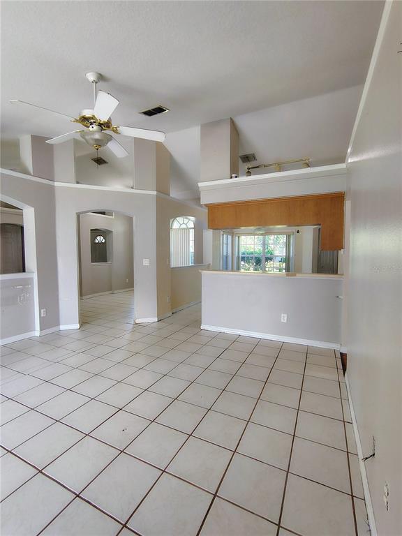A living area with white tile floors, a ceiling fan, and an open kitchen pass-through — 3248 SAWGRASS CREEK CIRCLE, ST CLOUD, FL