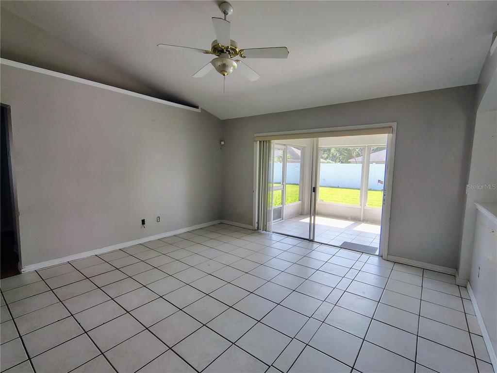 A living room with white tile floors, a ceiling fan, and sliding glass doors — 3248 SAWGRASS CREEK CIRCLE, ST CLOUD, FL
