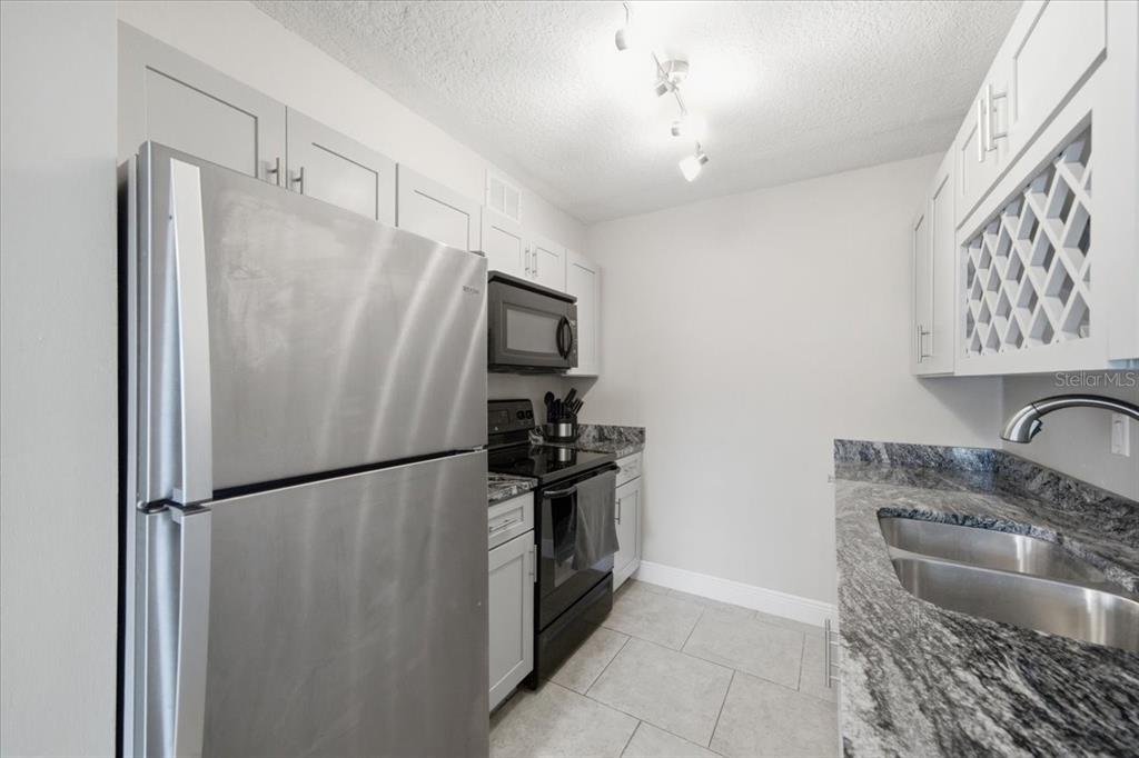 A kitchen with stainless steel appliances, white cabinets, and granite countertops — 4843 COQUINA KEY DRIVE SE UNIT A, ST PETERSBURG, FL