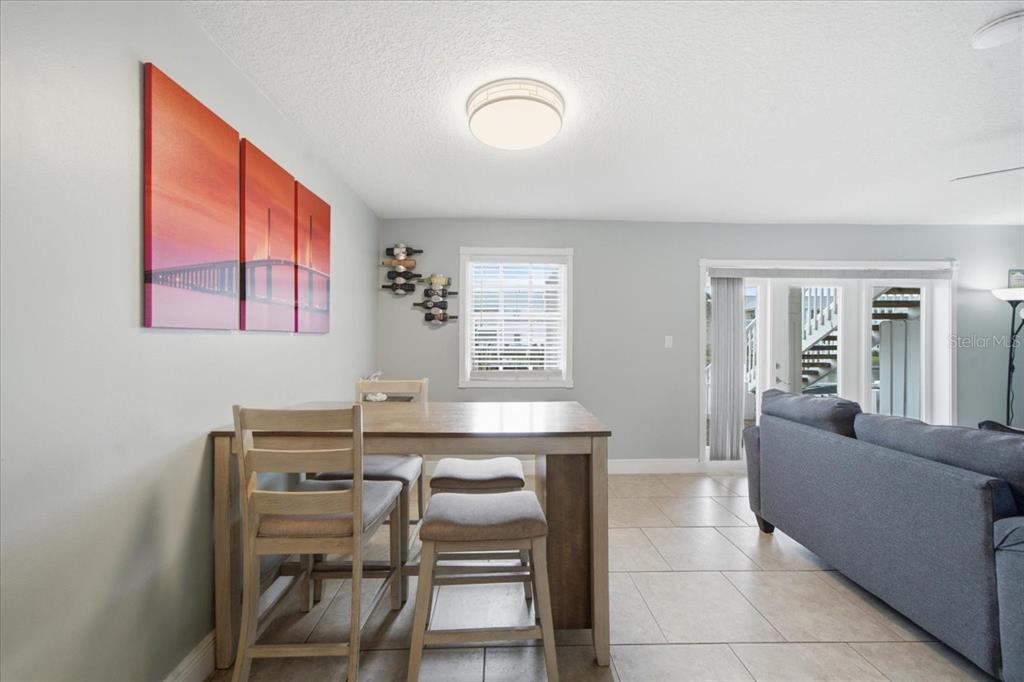A dining area with a wooden table and chairs sits next to a living room — 4843 COQUINA KEY DRIVE SE UNIT A, ST PETERSBURG, FL