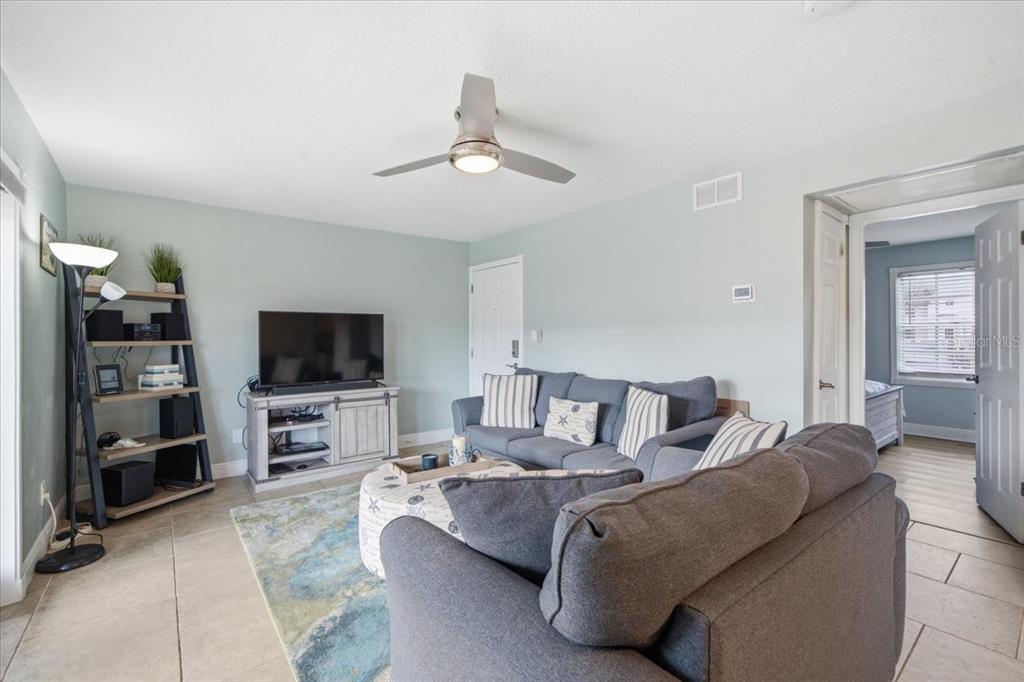 A living room features a grey sectional sofa, a television on a console, and tile flooring — 4843 COQUINA KEY DRIVE SE UNIT A, ST PETERSBURG, FL