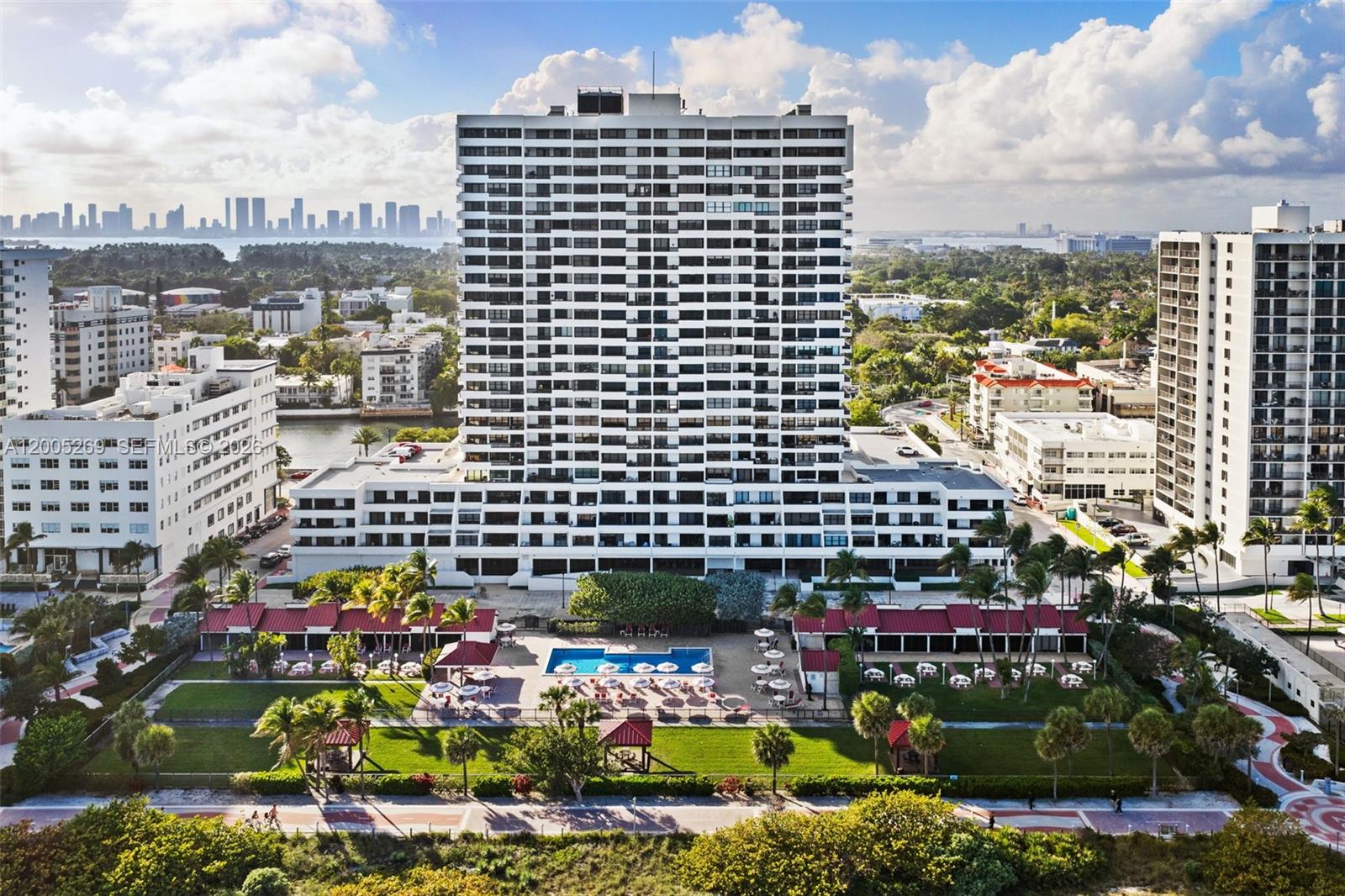 An aerial view shows a tall residential building with a swimming pool and landscaped grounds — 2555 Collins Ave # 1002, Miami Beach FL 33140, MIAMI BEACH, FL