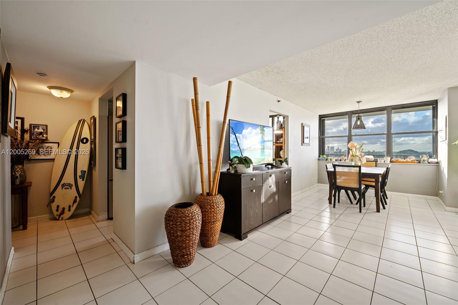 A dining area and entryway feature white tile floors, a surfboard, and large windows — 2555 Collins Ave # 1002, Miami Beach FL 33140, MIAMI BEACH, FL