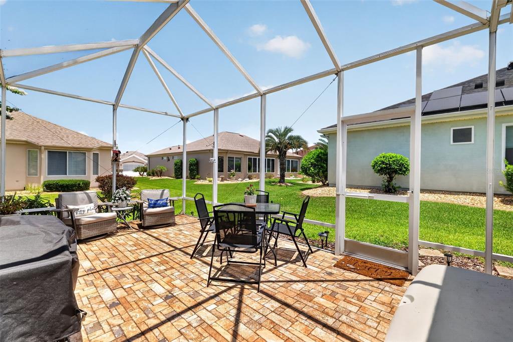A screened-in patio with brick pavers, outdoor furniture, and a view of neighboring houses — 9524 SE 124TH LOOP, SUMMERFIELD, FL