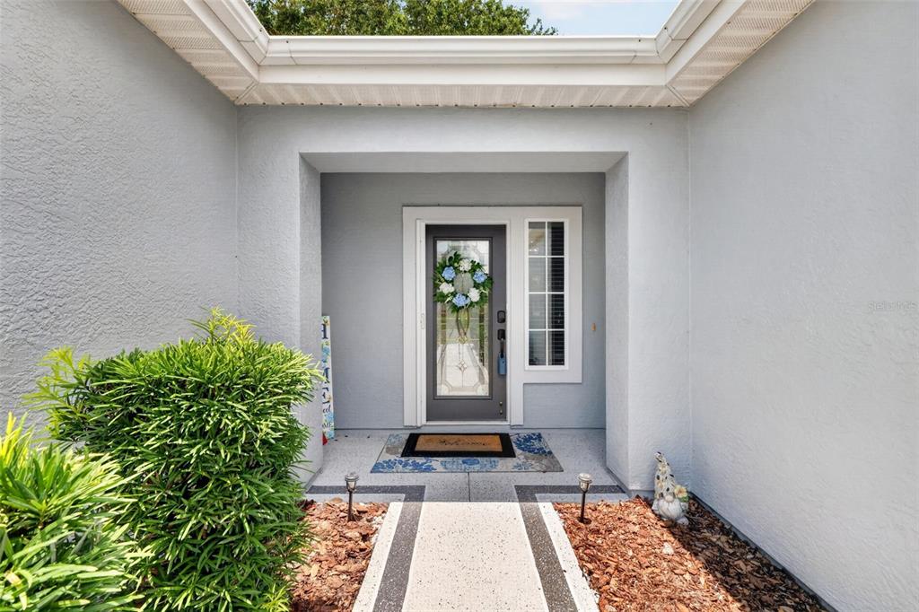 The front entrance of a house features a gray door with glass panels and a wreath — 9524 SE 124TH LOOP, SUMMERFIELD, FL