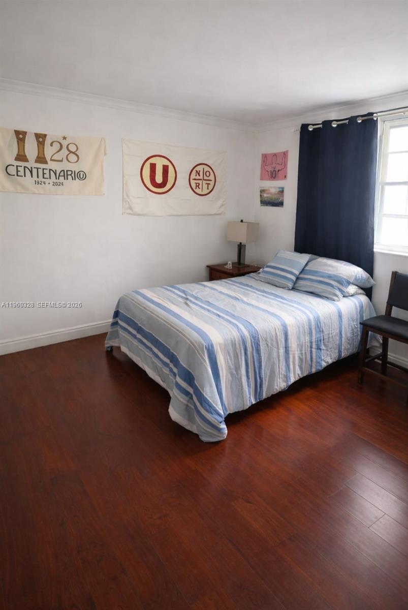 A bedroom features dark wood flooring, a bed with blue striped bedding, and wall banners — 1470 NE 125th Ter # 701, North Miami FL 33161, NORTH MIAMI, FL