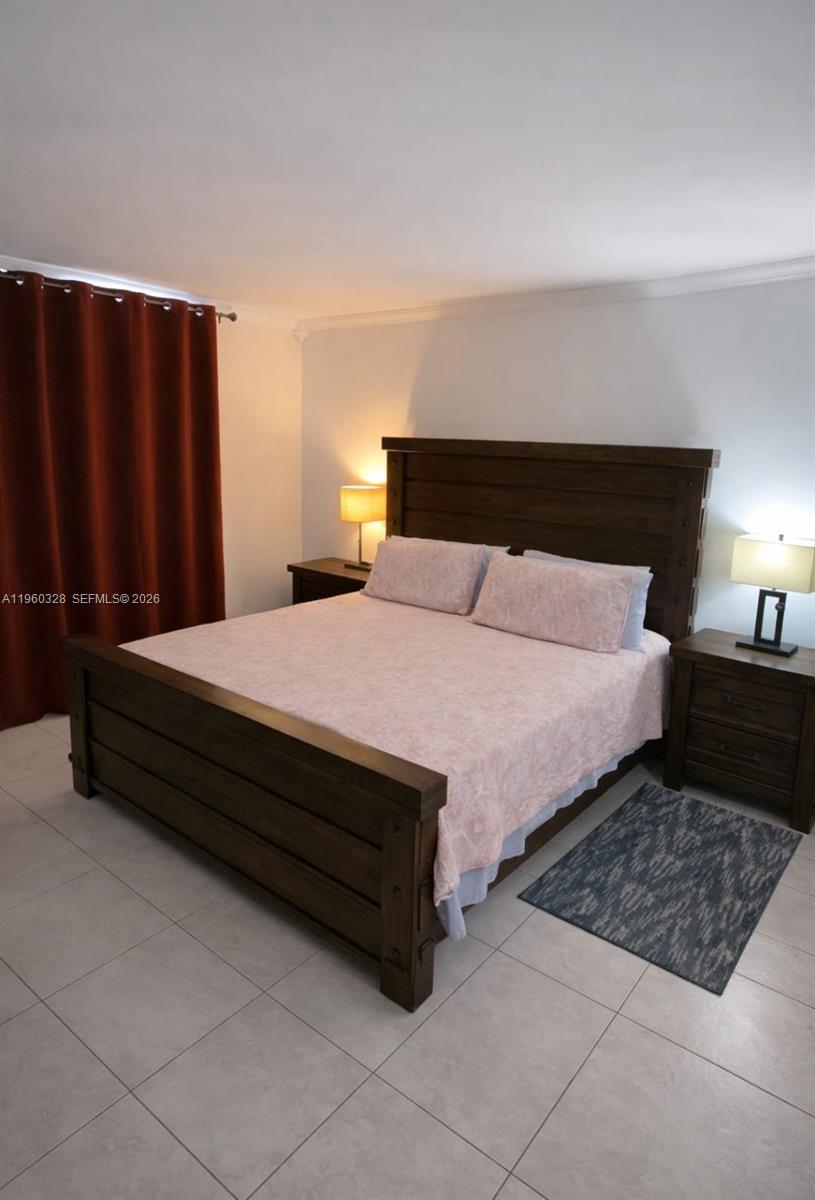 A bedroom features a dark wood bed frame, two nightstands with lamps, and tile flooring — 1470 NE 125th Ter # 701, North Miami FL 33161, NORTH MIAMI, FL