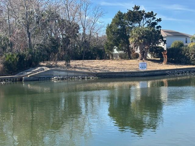 A vacant waterfront lot features a concrete seawall and a small boat ramp — 34 COLECHESTER LANE UNIT C, PALM COAST, FL