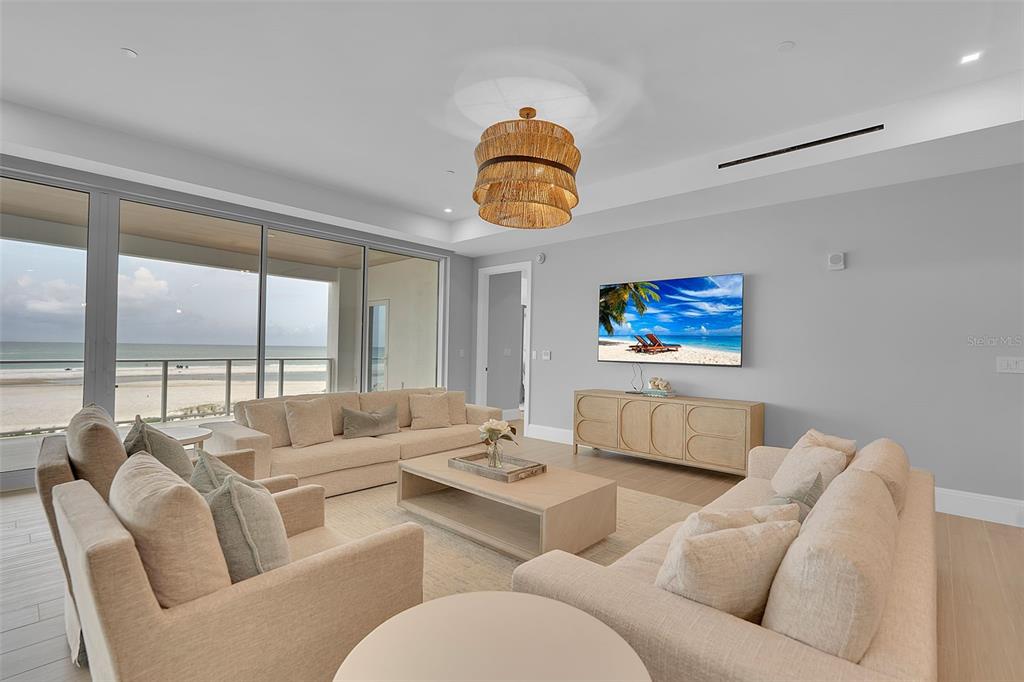 A bright living room features two beige sofas, a wooden coffee table, and ocean views — 70 AVENIDA VENECCIA UNIT 201, SARASOTA, FL