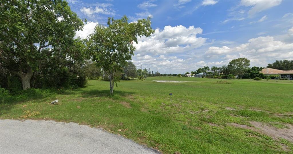 A grassy, vacant residential lot features a few trees and a small white marker post — 17172 SPICE LANE, PUNTA GORDA, FL