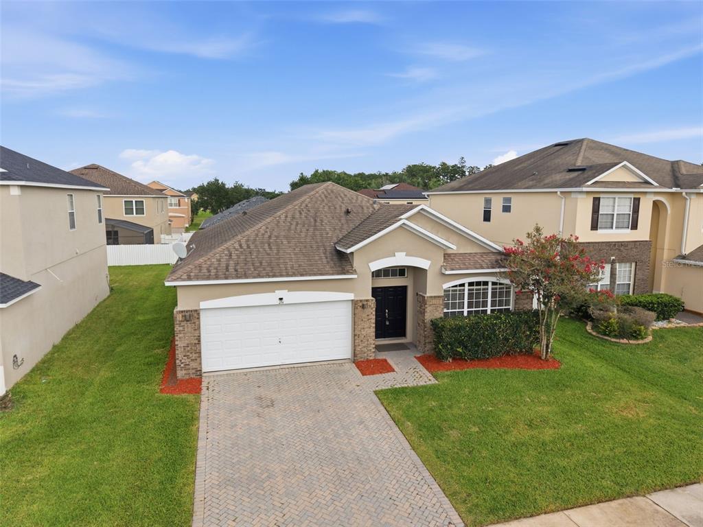 A single-story suburban house with a two-car garage, brick accents, and a paved driveway — 231 DOE RUN DRIVE, WINTER GARDEN, FL