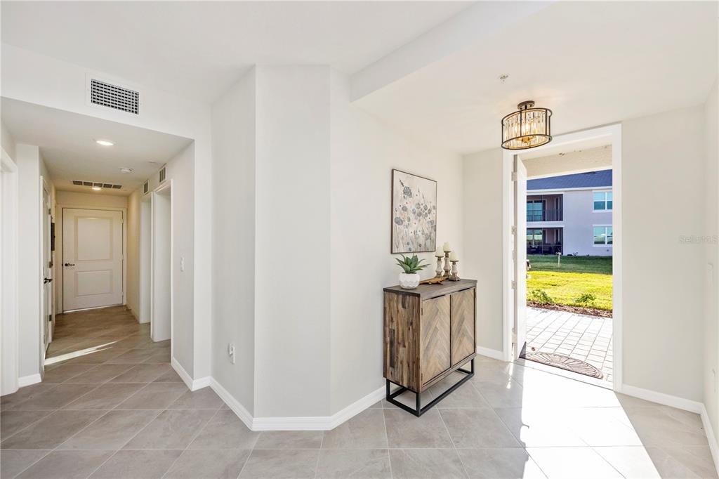An entryway with tile flooring, a wooden cabinet, and an open door leading outside — 17715 BORACAY COURT UNIT 101, VENICE, FL