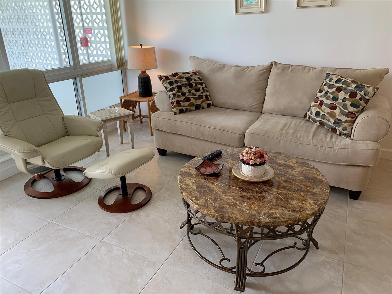 A living room features a beige sofa, a matching recliner with ottoman, and a marble-topped table — 3205 SE 7th Street # 201, Pompano Beach FL 33062, POMPANO BEACH, FL