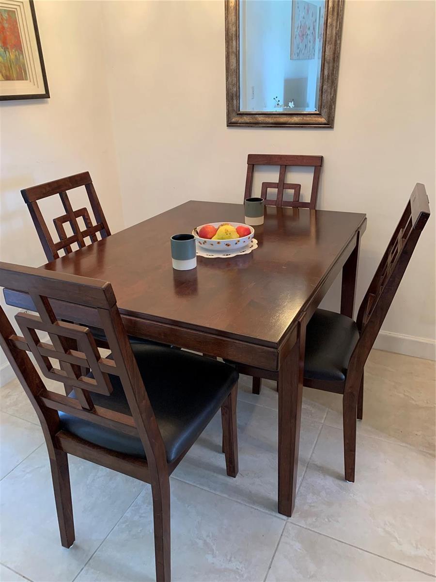 A dark wood dining table with four matching chairs sits on a light tiled floor — 3205 SE 7th Street # 201, Pompano Beach FL 33062, POMPANO BEACH, FL