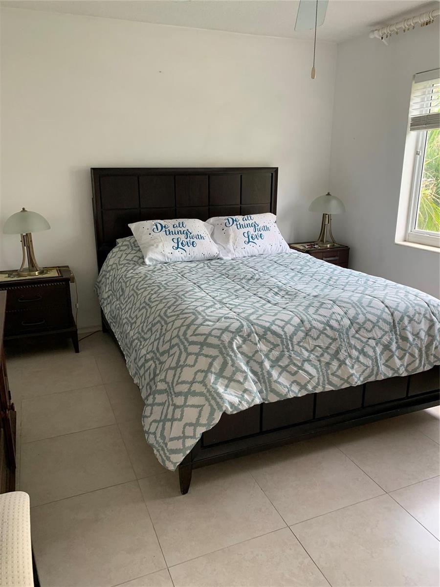 A bedroom features a dark wood bed frame, patterned bedding, and two matching bedside lamps — 3205 SE 7th Street # 201, Pompano Beach FL 33062, POMPANO BEACH, FL