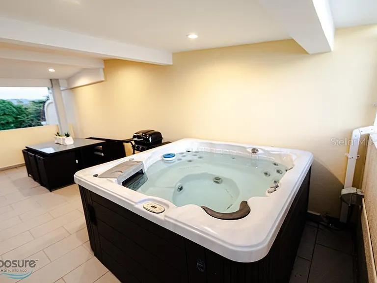 A hot tub sits on a tiled balcony next to a black dining set — 429 KM 1.2 BARRIO CALVACHE #312, RINCON, PR