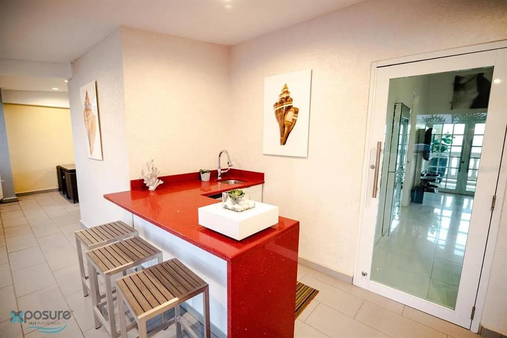 A wet bar with a red countertop and three metal stools sits in a room — 429 KM 1.2 BARRIO CALVACHE #312, RINCON, PR