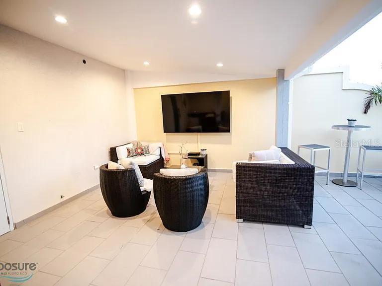 An outdoor patio features wicker furniture, a wall-mounted television, and light-colored tile flooring — 429 KM 1.2 BARRIO CALVACHE #312, RINCON, PR
