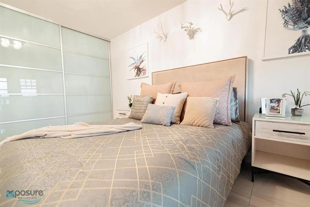A bedroom features a bed with a tan headboard, patterned bedding, and wall-mounted deer antlers — 429 KM 1.2 BARRIO CALVACHE #312, RINCON, PR