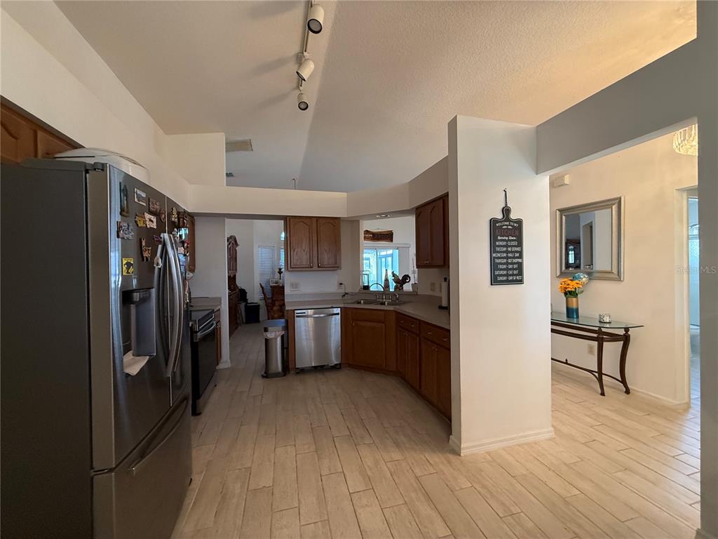 A kitchen with wood cabinets, stainless steel appliances, and light-colored tile flooring — 25607 BELLE HELENE, LEESBURG, FL