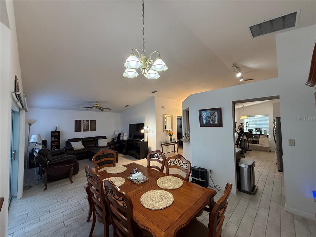 A dining area with a wooden table and chairs sits in front of a living room — 25607 BELLE HELENE, LEESBURG, FL