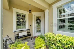 A covered front porch features a black bench, a glass-paneled door, and large windows — 210 LATITUDE PLACE, APOLLO BEACH, FL