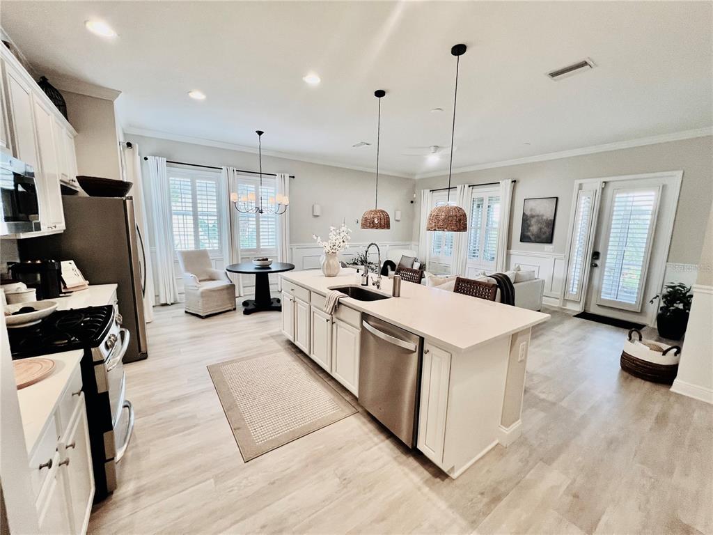 A modern kitchen features white cabinets, a large island with a sink, and light flooring — 210 LATITUDE PLACE, APOLLO BEACH, FL