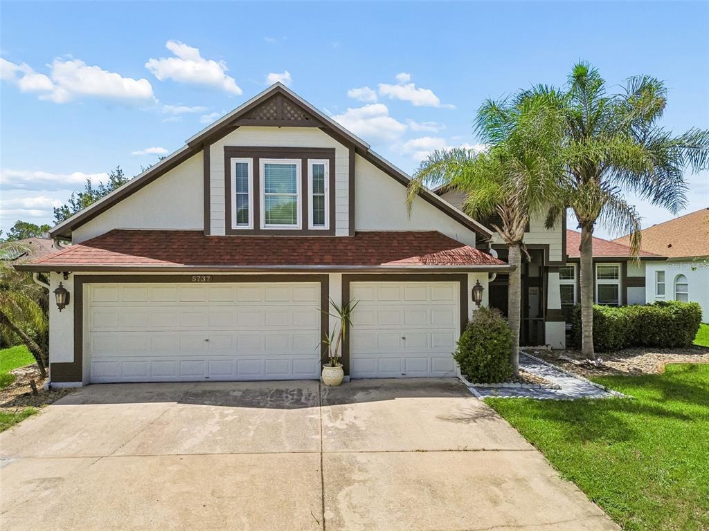 A two-story house features a two-car garage, a red shingled roof, and a palm tree — 5737 WYNSTONE LANE, ZEPHYRHILLS, FL