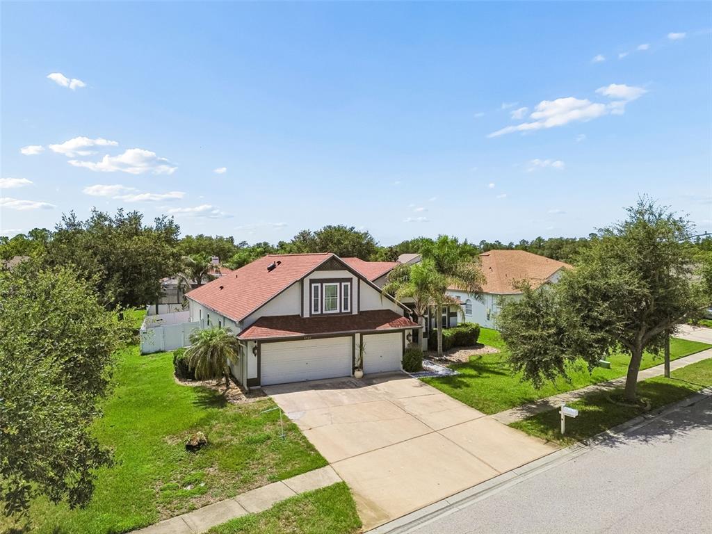 An aerial view of a two-story house with a red roof and a concrete driveway — 5737 WYNSTONE LANE, ZEPHYRHILLS, FL