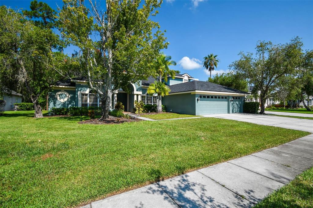 A teal single-story house with a three-car garage and a large front lawn — 10526 GREENCREST DRIVE, TAMPA, FL