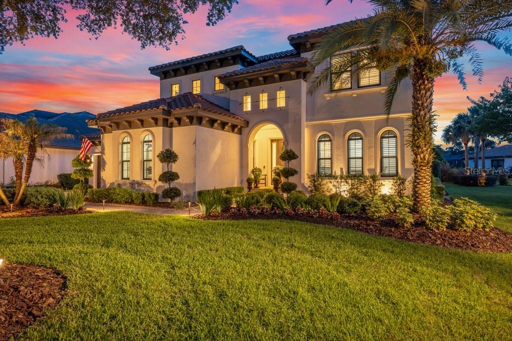 A two-story Mediterranean-style house with a tiled roof and arched windows at sunset — 5201 ALAFIA FALLS DRIVE, LITHIA, FL