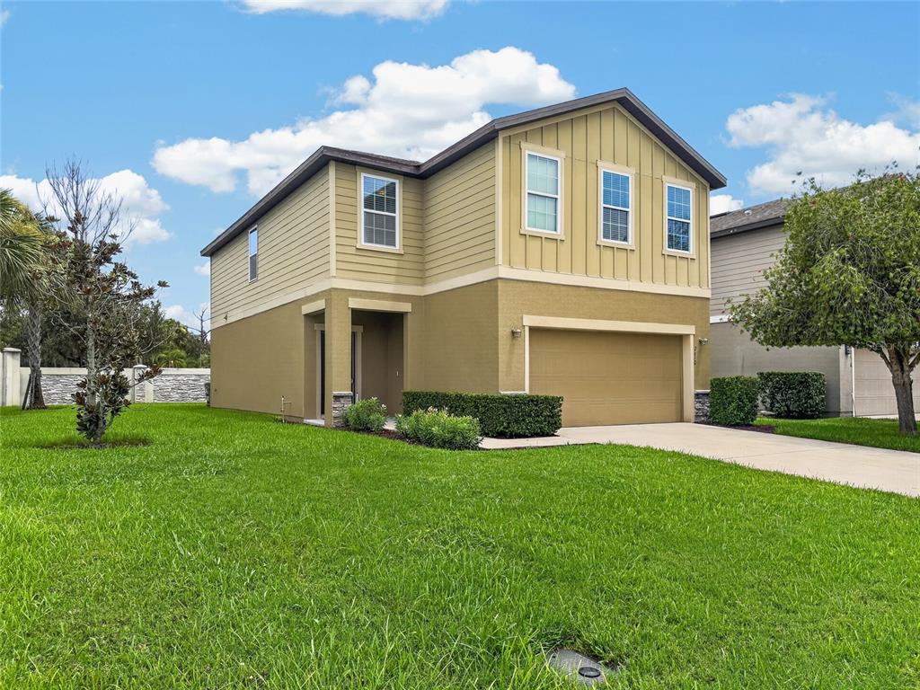 A two-story house with tan stucco and siding, a two-car garage, and a front lawn — 2610 FLICKER COVE, SANFORD, FL