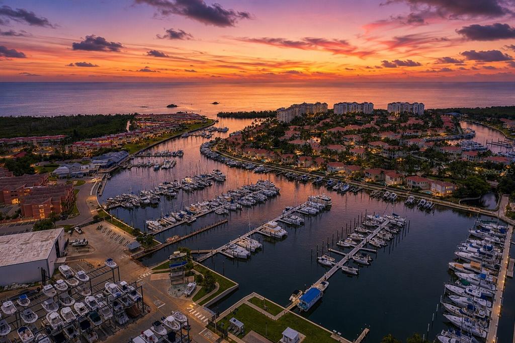 An aerial view of a marina filled with boats at sunset near a coastal residential community — 3329 SUNSET KEY CIRCLE UNIT 204, PUNTA GORDA, FL
