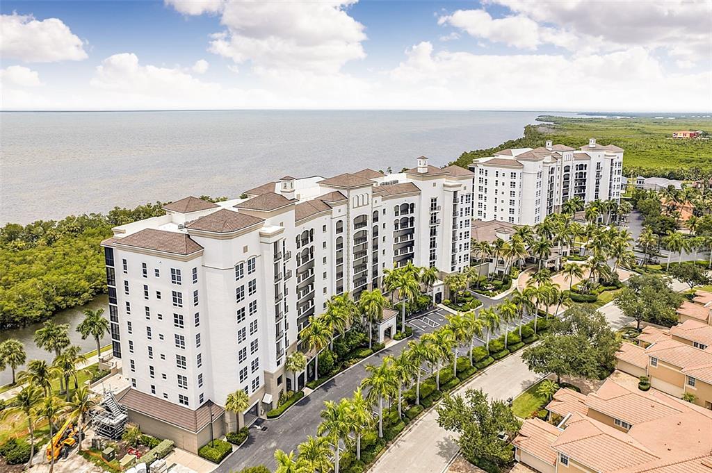 An aerial view shows a large multi-story residential building situated near a coastal mangrove forest — 3329 SUNSET KEY CIRCLE UNIT 204, PUNTA GORDA, FL