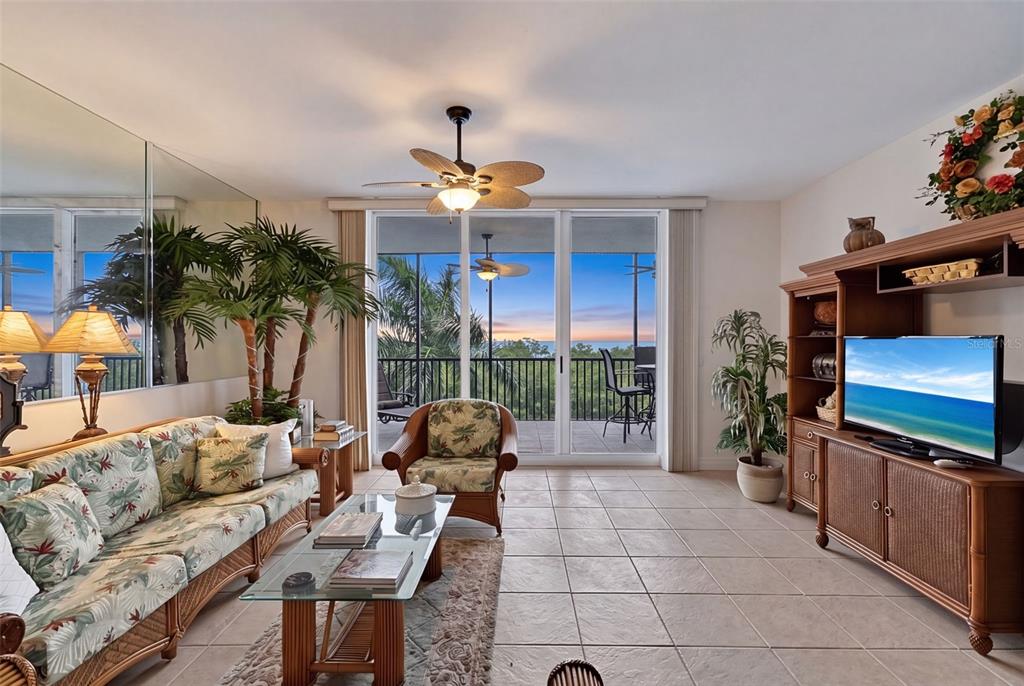 A living room with wicker furniture, a ceiling fan, and a balcony overlooking the ocean — 3329 SUNSET KEY CIRCLE UNIT 204, PUNTA GORDA, FL