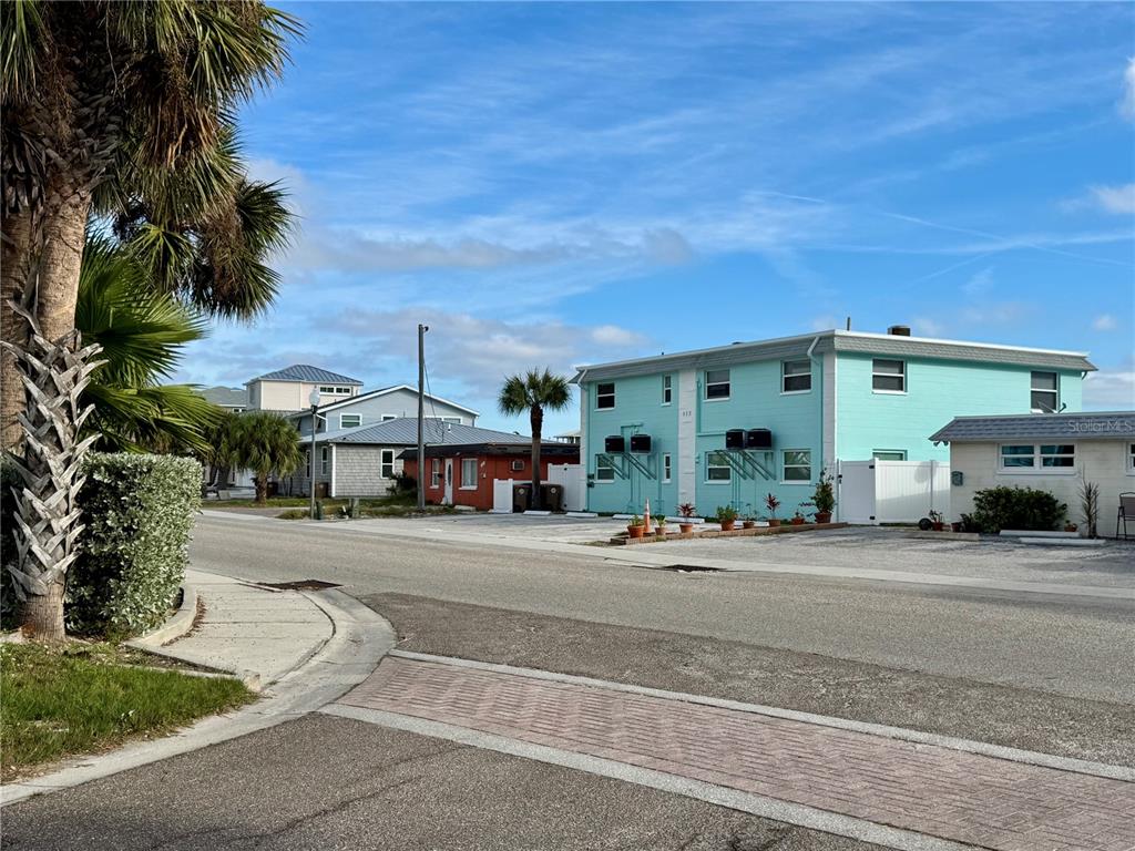 A street view shows a teal two-story building next to smaller houses and palm trees — 117 140TH AVENUE E UNIT A, MADEIRA BEACH, FL