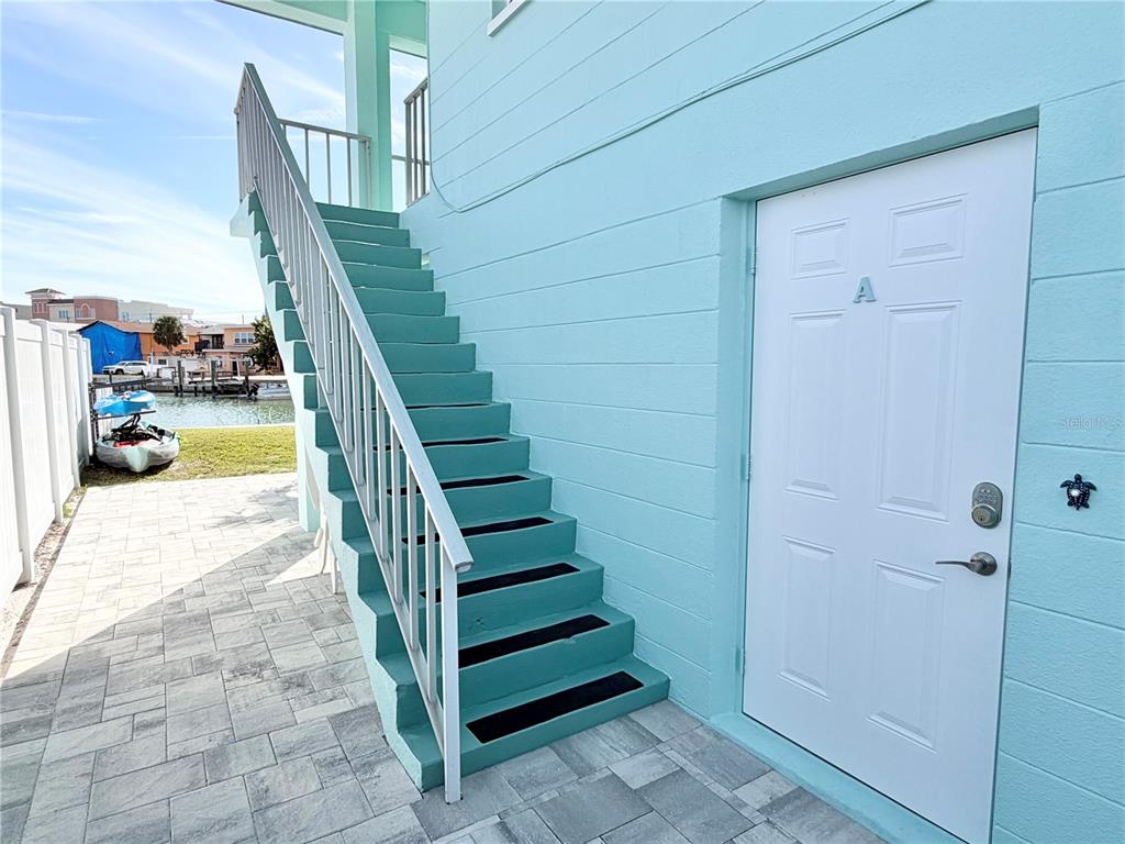 An exterior view shows a light blue building with a white door labeled A and stairs — 117 140TH AVENUE E UNIT A, MADEIRA BEACH, FL