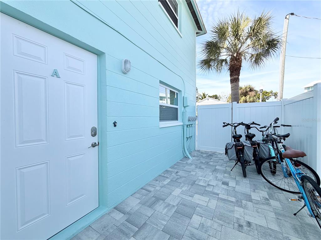A light blue exterior wall features a white door labeled A and a paved patio — 117 140TH AVENUE E UNIT A, MADEIRA BEACH, FL