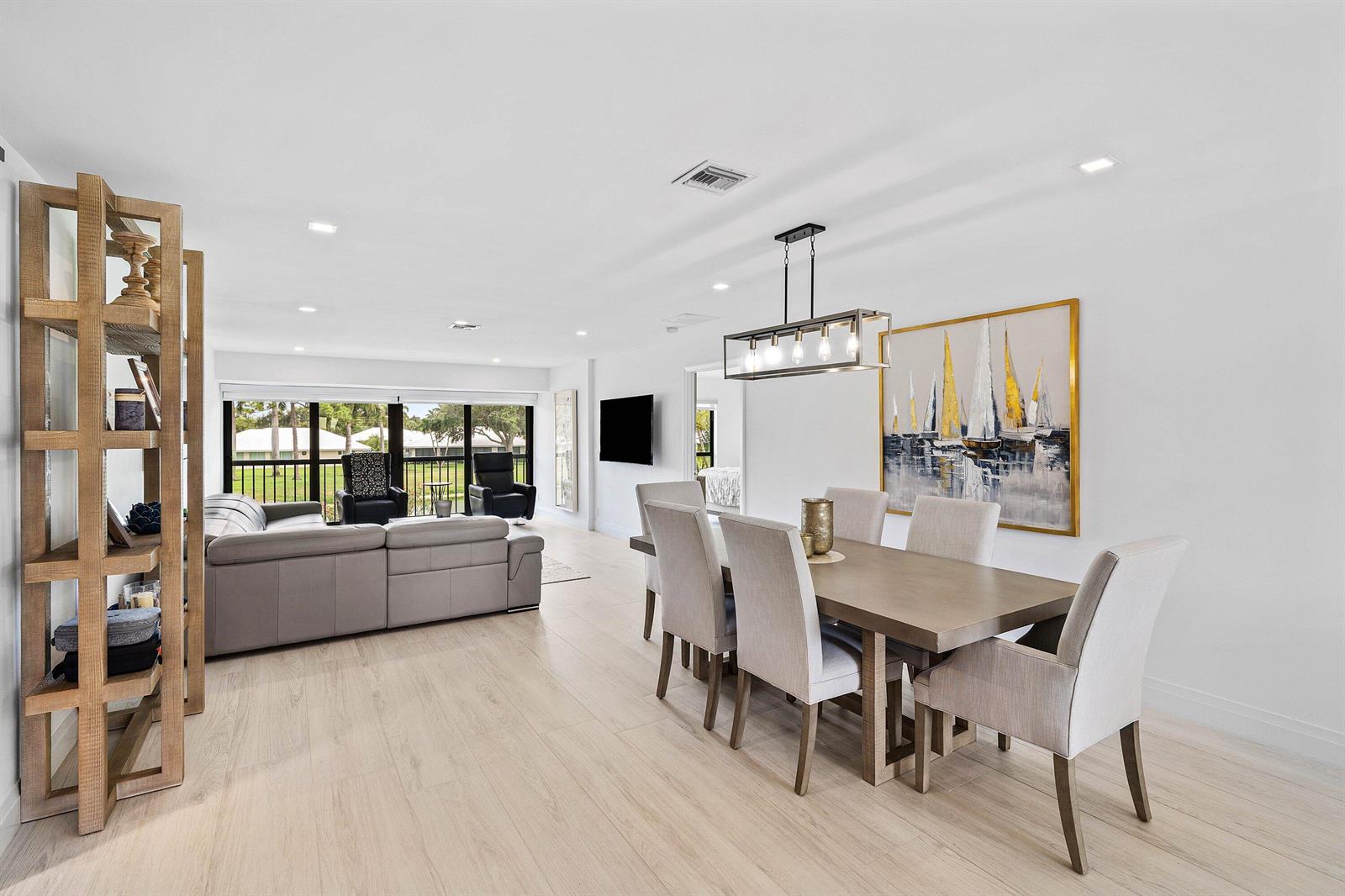 A bright open-concept living and dining area features light wood flooring and modern neutral furniture — 3676 Quail Ridge Drive N, Boynton Beach FL 33436, BOYNTON BEACH, FL
