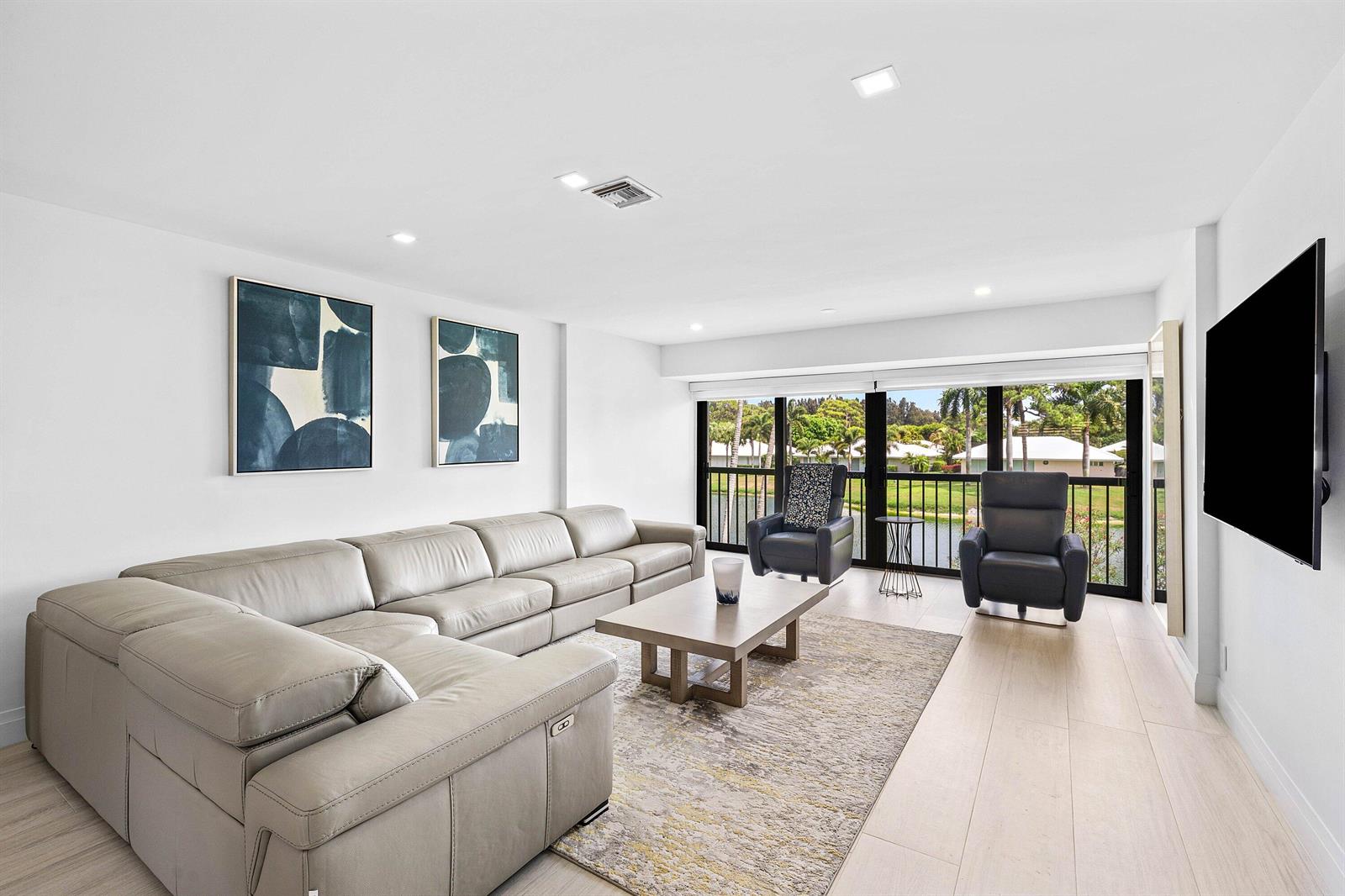 A modern living room features a large gray sectional, two armchairs, and floor-to-ceiling windows — 3676 Quail Ridge Drive N, Boynton Beach FL 33436, BOYNTON BEACH, FL