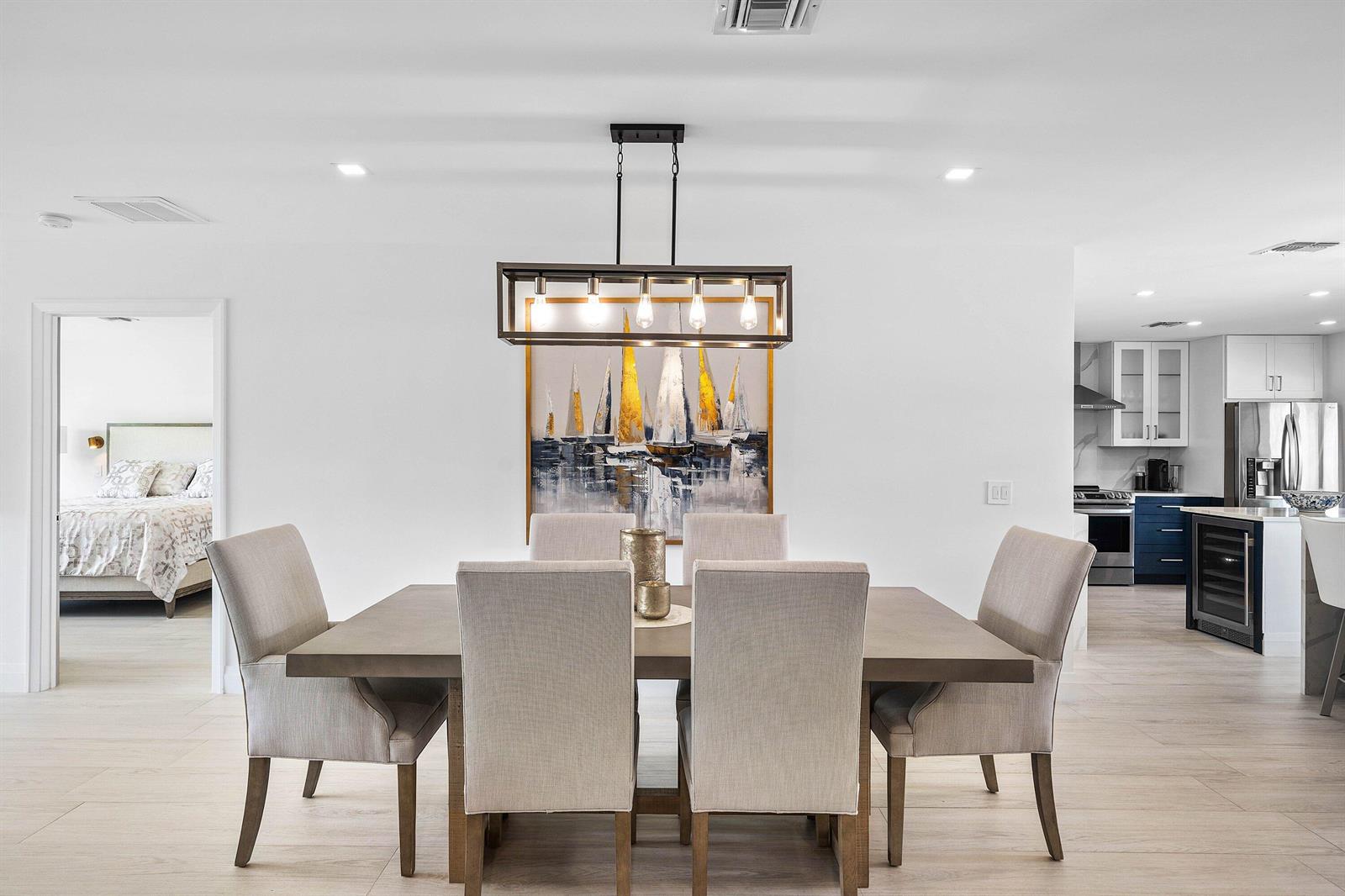A dining room features a rectangular wooden table, six upholstered chairs, and a linear chandelier — 3676 Quail Ridge Drive N, Boynton Beach FL 33436, BOYNTON BEACH, FL