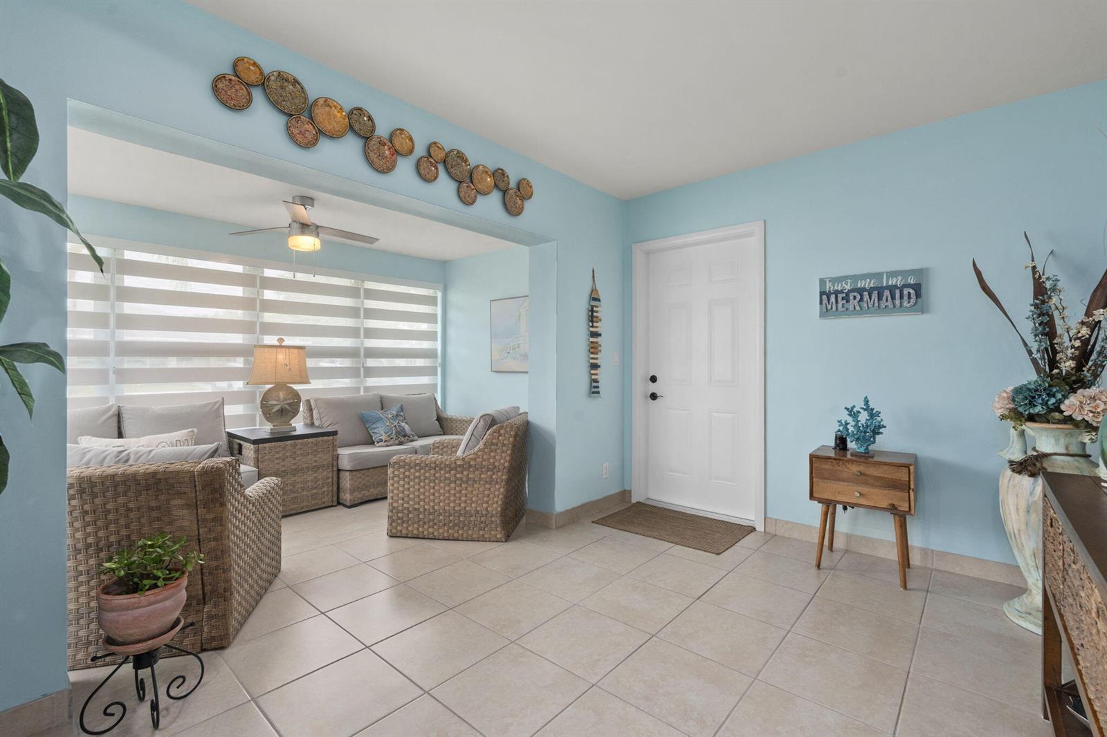 A light blue entryway features tile flooring, wicker furniture, and a white front door — 1177 S Drive Circle # B, Delray Beach FL 33445, DELRAY BEACH, FL