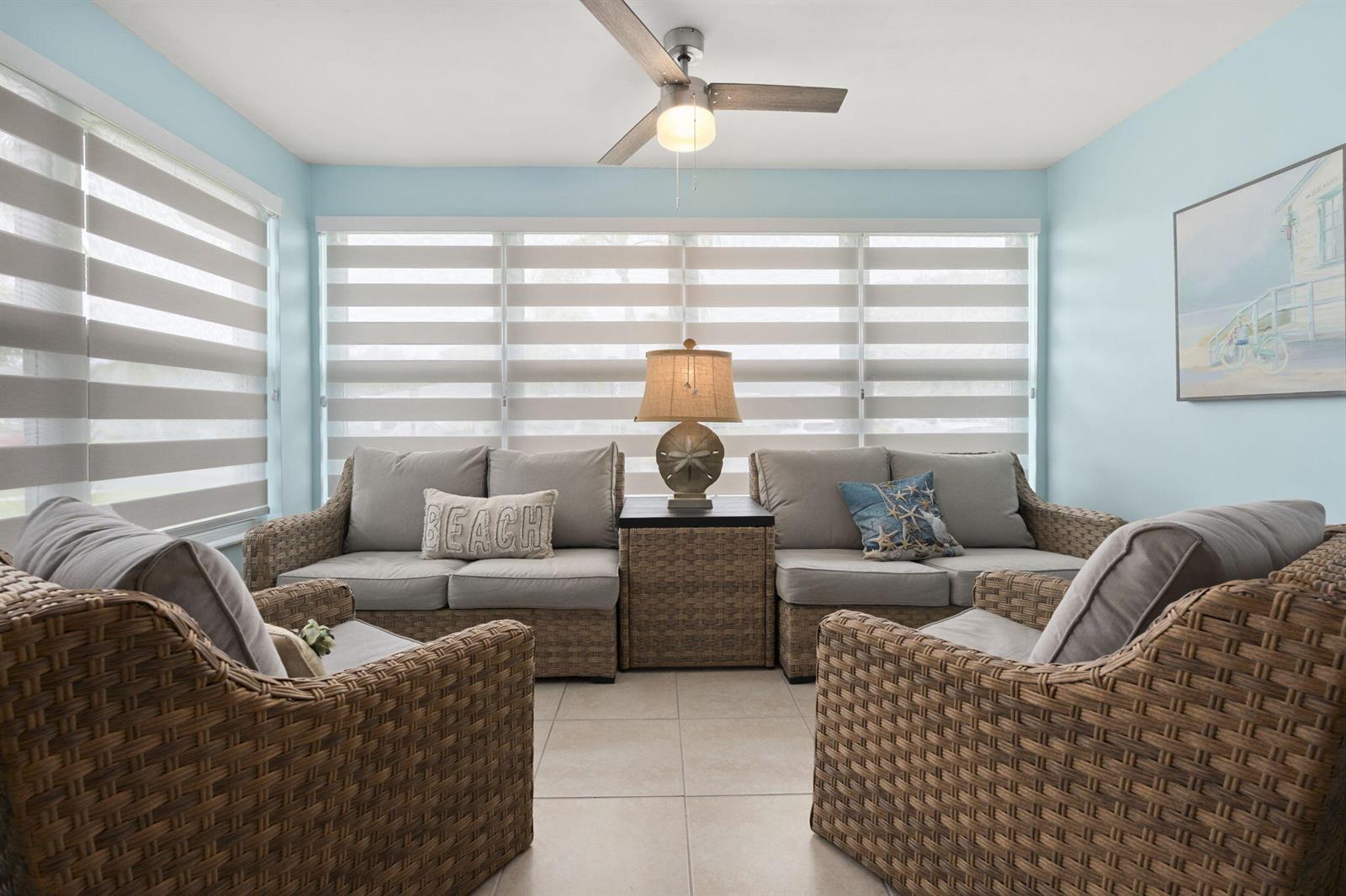 A sunroom features wicker furniture, light blue walls, tile flooring, and striped window shades — 1177 S Drive Circle # B, Delray Beach FL 33445, DELRAY BEACH, FL