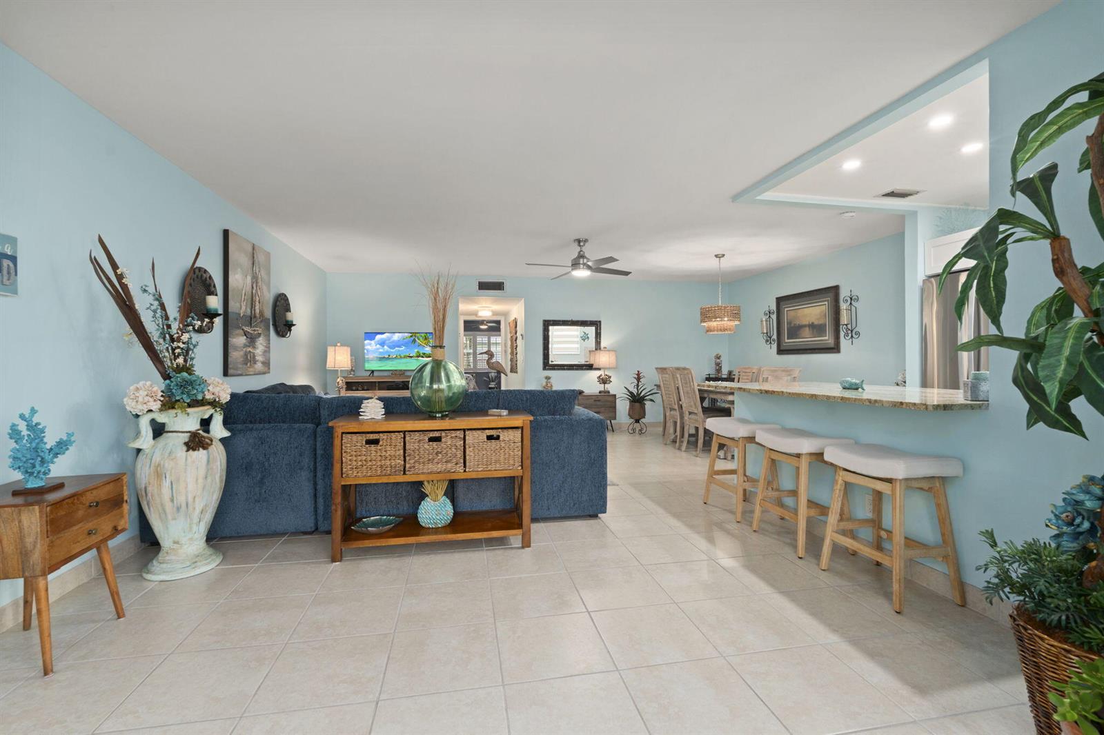 A living room with a blue sectional, breakfast bar, and light blue walls — 1177 S Drive Circle # B, Delray Beach FL 33445, DELRAY BEACH, FL