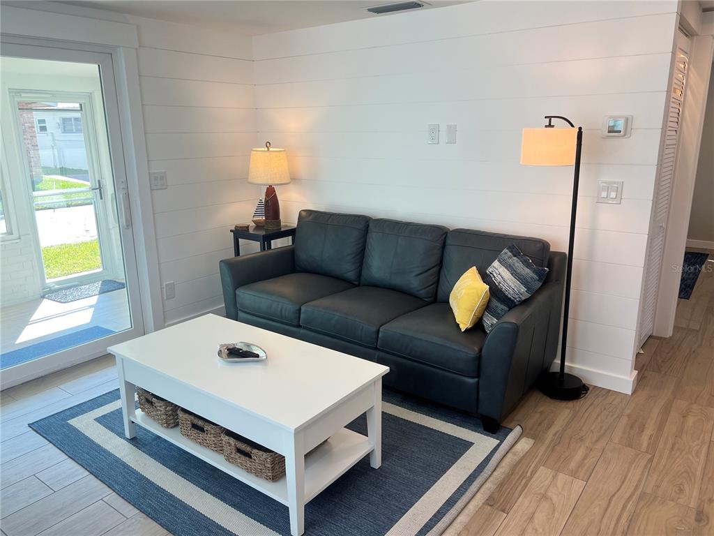 A living room features a dark sofa, white coffee table, and white shiplap walls — 6020 MIDNIGHT PASS ROAD UNIT 54, SARASOTA, FL